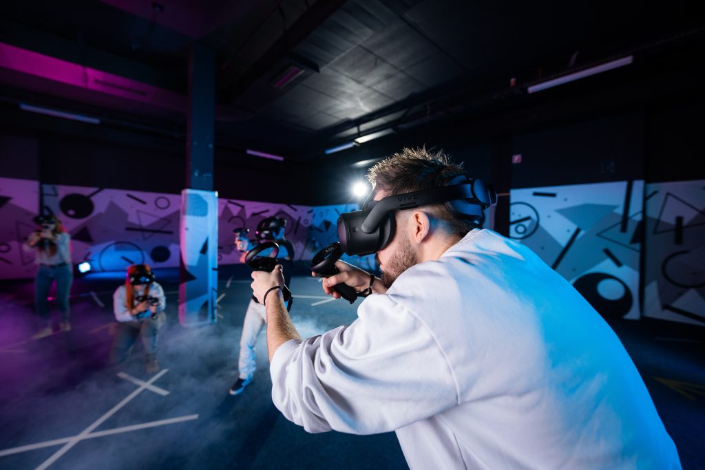 Jeune homme visant avec des manettes VR dans une salle de jeux.