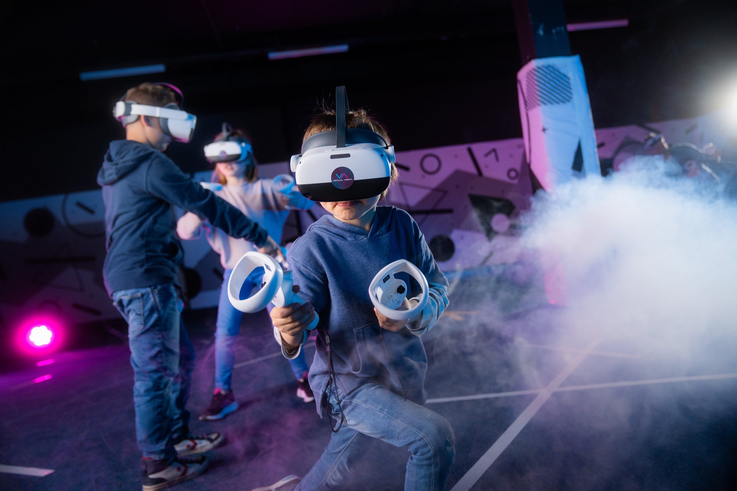 Kinder spielen in einer virtuellen Realität mit VR-Headsets und Controllern.