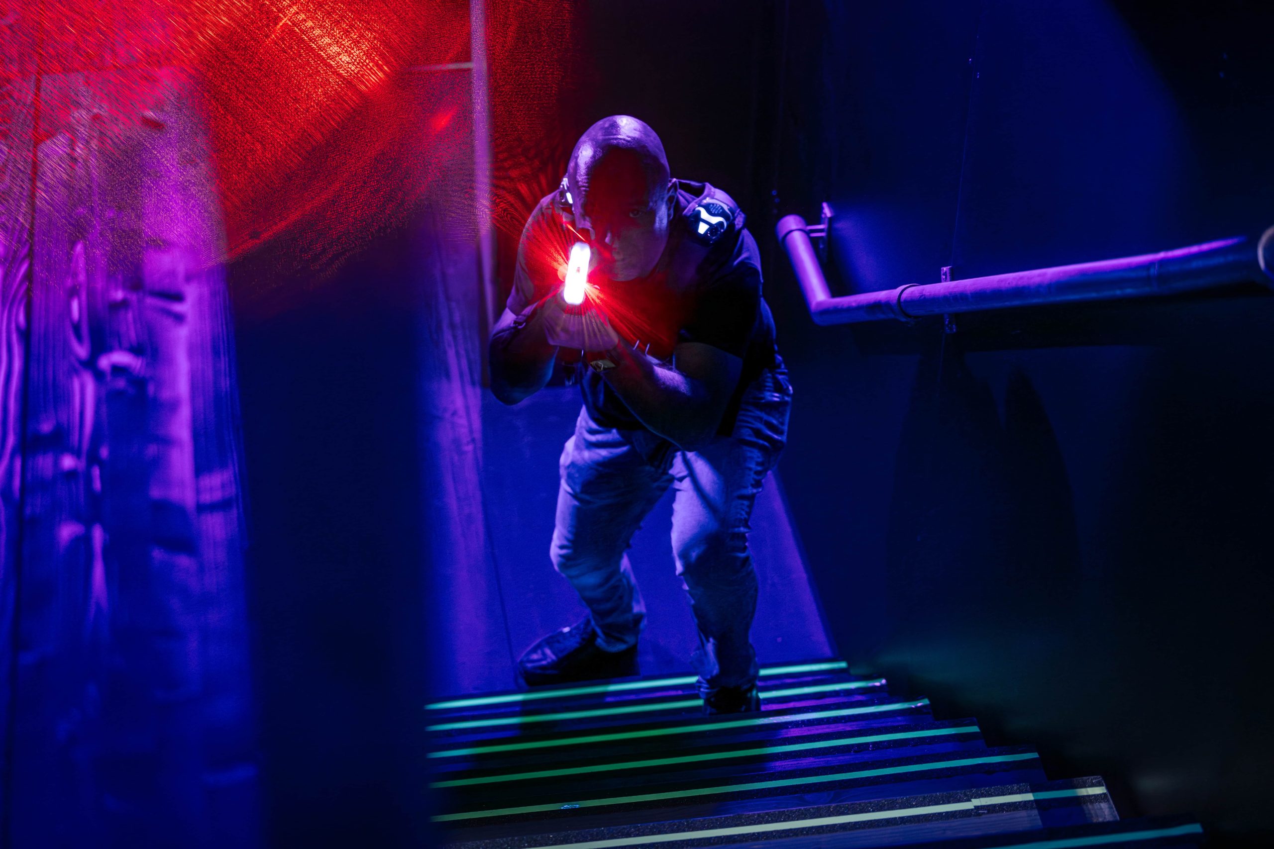 Joueur équipé pour le lasertag prêt pour l'action dans une arène éclairée au néon.